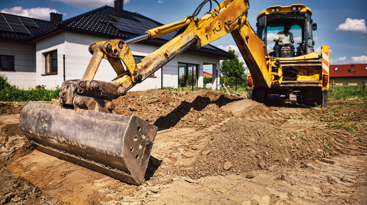 Fouille d'excavation pour piscine montrant un talus en pente douce dans sol sableux, avec niveau laser positionné sur la pente pour vérifier l'angle de sécurité